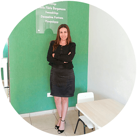 Izabel Morais em pé, de braços cruzados, diante de uma parede verde